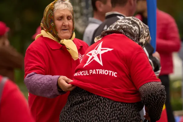 A woman gets help with taking off a red shirt decorated with the hammer and sickle after attending a rally of the Russia-friendly Patriotic Electoral Bloc in Chisinau, Moldova, Thursday, Sept. 25, 2025, ahead of parliamentary elections taking place on Sept. 28. (AP Photo/Vadim Ghirda)ASSOCIATED PRESS