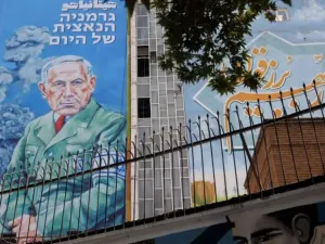 People walk past a billboard with a caricature of Israel's Prime Minister Benjamin Netanyahu, on a street in Tehran, Iran, August 10, 2025. (credit: Majid Asgaripour/West Asia News Agency/Reuters)