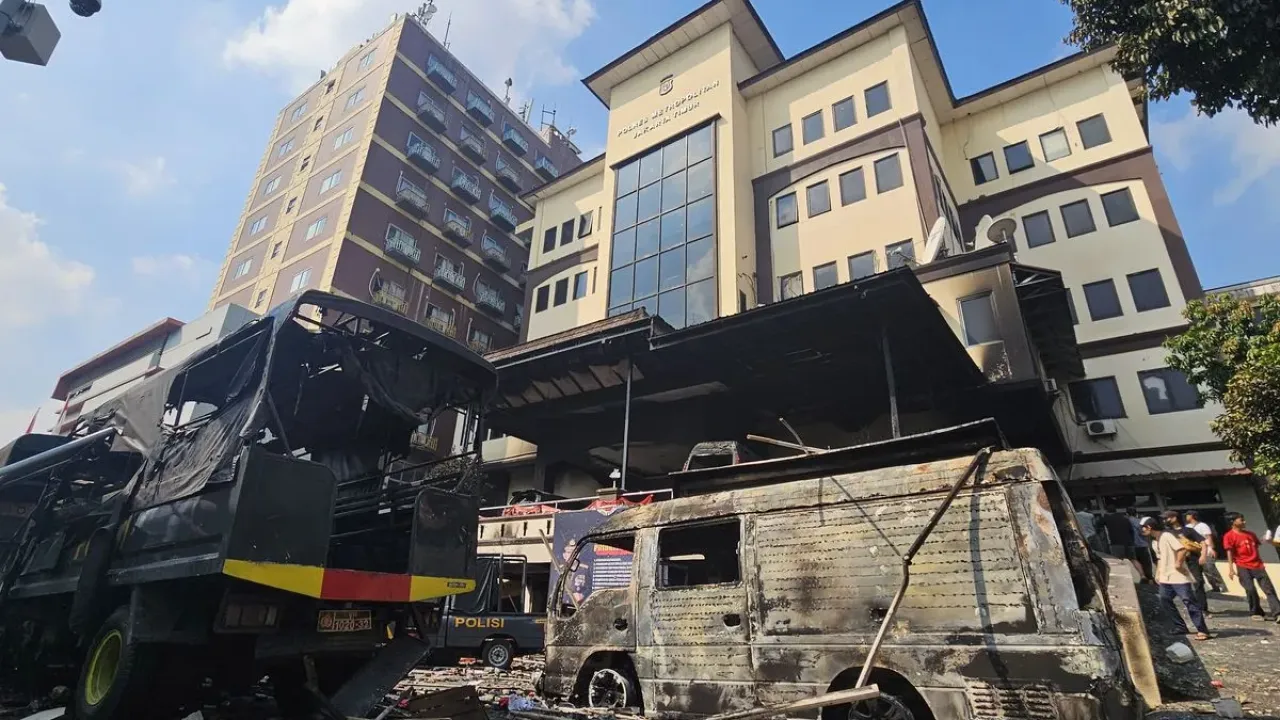 Warga mengamati kendaraan dinas kepolisian yang hangus terbakar di Mapolres Jakarta Timur, Jakarta, Sabtu (30/8/2025). Puluhan mobil dan sejumlah ruangan hangus terbakar akibat aksi unjuk rasa yang berlangsung ricuh. 