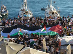 A Palestinian flag is seen as people gather at the port of Ermoupolis before the departure of two sailing boats, Electra and Oxygen, part of the Global Sumud Flotilla aiming to reach Gaza and break Israel