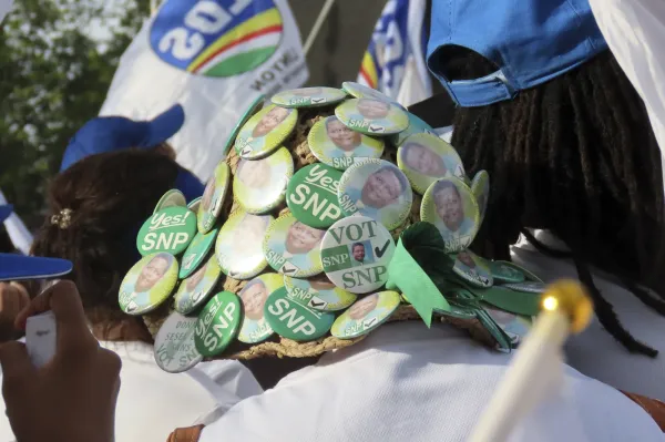 A supporter wears a hat pinned with the symbols of the Seychelles National Party, a former opposition political party, during a campaign rally at Freedom Square in Victoria, Seychelles, Sunday, Sep. 21, 2025. (AP Photo/Emilie Chetty)ASSOCIATED PRESS