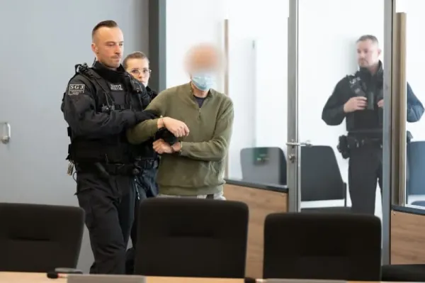 The main defendant Jian G. (C) is escorted into the courtroom at the Dresden Higher Regional Court (OLG) prior to the announcement of the verdict in a high-profile espionage case. The proceedings concern a former employee of Alternative for Germany (AfD) parliamentarian Maximilian Krah and his alleged accomplice, accused of passing sensitive information to foreign actors. Sebastian Kahnert/dpa-pool/dpa