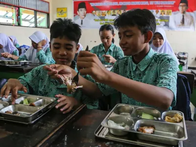 Seorang siswa berbagi lauk pauk kepada teman sebangkunya saat menyantap makanan program Makan Bergizi Gratis (MBG) di SMP Negeri 9 Kota Semarang, Jawa Tengah, Selasa (9/9/2025). Pemerintah Provinsi Jawa Tengah mencatat capaian realisasi penerima manfaat program MBG per tanggal 26 Agustus 2025 di provinsi itu sebanyak 2,7 juta orang penerima manfaat atau mencapai 28,14 persen dari total target sasaran yakni sebesar 9,6 juta orang penerima manfaat yang meliputi siswa sekolah, ibu hamil, ibu menyusui, dan balita. ANTARA FOTO/Makna Zaezar/foc.