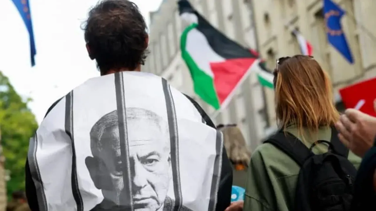 A pro-Palestinian activist is wrapped in an image depicting Prime Minister Benjamin Netanyahu behind bars as demonstrators march towards the Slovenian Prime Minister's Office, in Ljubljana, Slovenia, August 6, 2025. (credit: REUTERS/BORUT ZIVULOVIC)