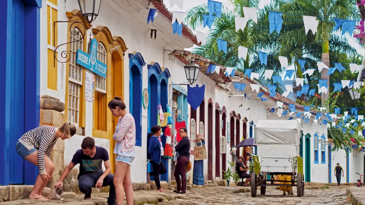 A cobble-stoned street with small flag garlands hung between the colonal-style buildings.