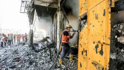 A firefighter sprays water on a building damaged in an Israeli air strike. Hasan Alzaanin/TASS via ZUMA Press/dpa