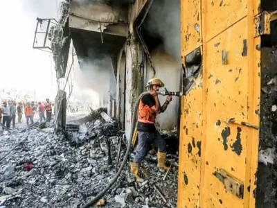 A firefighter sprays water on a building damaged in an Israeli air strike. Hasan Alzaanin/TASS via ZUMA Press/dpa
