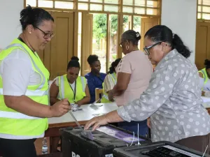 An election worker in a high-vis jacket helps a woman vote