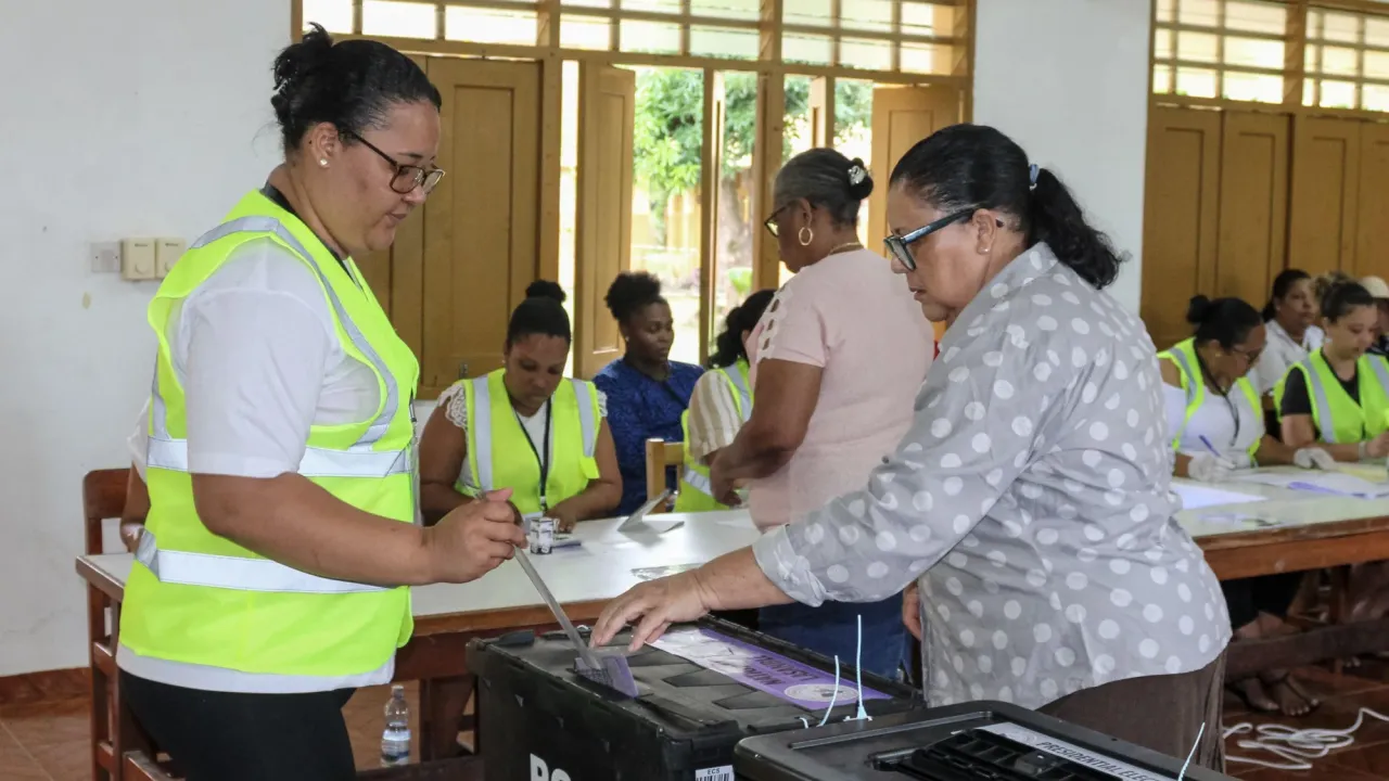 An election worker in a high-vis jacket helps a woman vote