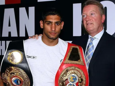 Frank Warren puts his arm around Amir Khan, who is holding his world titles