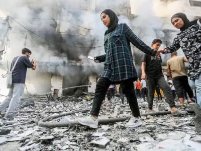 Palestinians move outside a building damaged in an Israeli air strike. Hasan Alzaanin/TASS via ZUMA Press/dpa