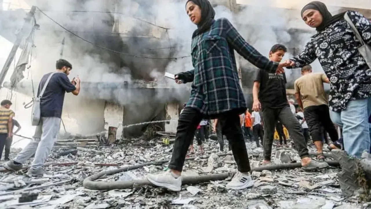 Palestinians move outside a building damaged in an Israeli air strike. Hasan Alzaanin/TASS via ZUMA Press/dpa