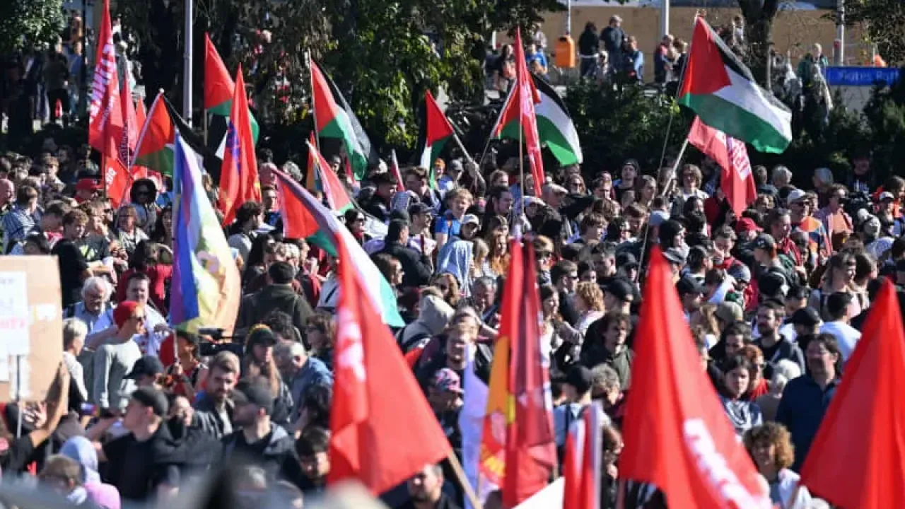 People hold up flags and signs during a pro-Palestine demonstration in Berlin. Annette Riedl/dpa