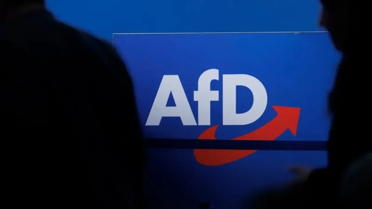 People walk in front of the party logo at the Alternative for Germany (AfD) party conference in Magdeburg. Carsten Koall/dpa
