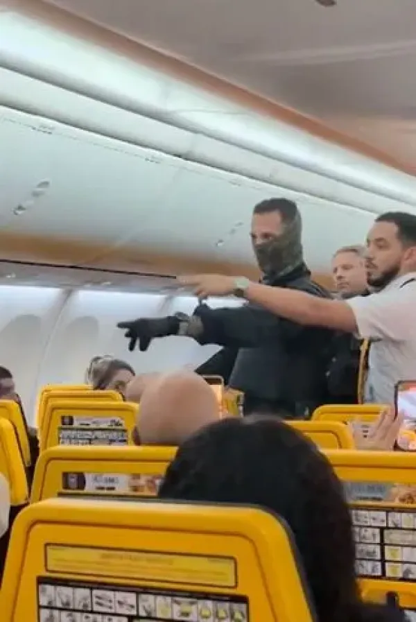 SWNS A Ryanair flight attendant points out unruly passengers to French police.