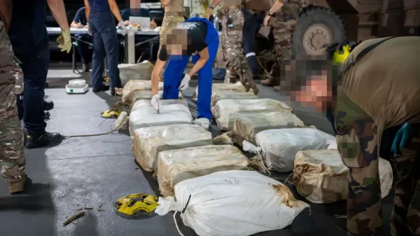 Uniformed men inspecting several plastic bags containing cocaine lying on the floor