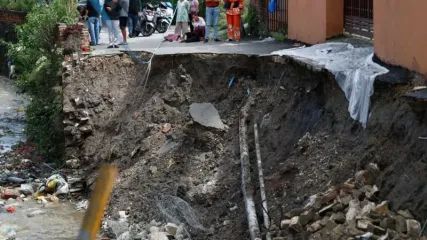 People look on as Kathmandu Metropolitan Police, with the assistance of local police, work to repair a road that collapsed due to heavy rainfall, damaging the section at Bafal. Skanda Gautam/SOPA Images via ZUMA Press Wire/dpa