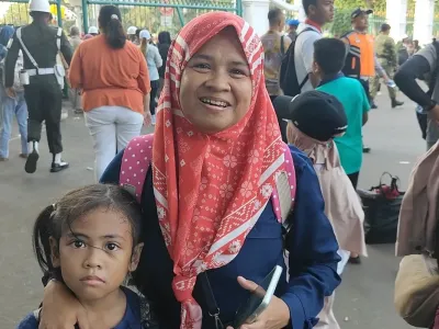 Sri Lestari, membawa serta anaknya ke HUT ke-80 TNI di Monas, Jakarta, Minggu (5/10/2025). Sri memperoleh kupon doorprize yang dibagikan oleh personel TNI dan berharap mendapatkan sepeda motor.