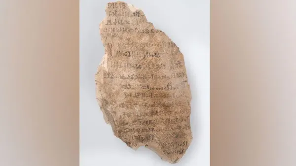 A record of work in the Valley of the Kings, 1550–1069 BC, limestone and pigment. It is a jagged roughly diamond shaped fragment of stone, which has faded black script across its width.