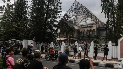 <span>People look at the West Nusa Tenggara Provincial Council office building, seen partially burned after being stormed, looted, and set on fire during a demonstration, in Mataram on Lombok Island, West Nusa Tenggara, on August 30, 2025. </span><div><span>STR</span><span>AFP</span></div>
