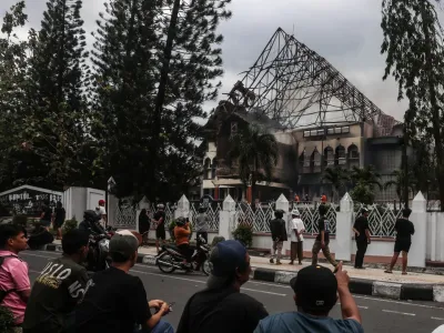 <span>People look at the West Nusa Tenggara Provincial Council office building, seen partially burned after being stormed, looted, and set on fire during a demonstration, in Mataram on Lombok Island, West Nusa Tenggara, on August 30, 2025. </span><div><span>STR</span><span>AFP</span></div>