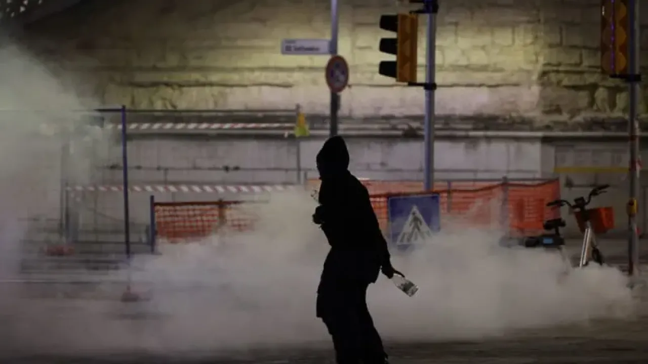 A protester throws glasses at police as they throw gas grenades during a protest in support of Palestine and the Global Sumud Flotilla in Bologna. Guido Calamosca/LaPresse via ZUMA Press/dpa