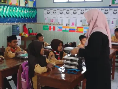 Guru di SDN Sendangsari, Kecamatan Bener, Purworejo, membagikan ompreng berisi menu makan siang gratis kepada siswa. Program Makan Bergizi Gratis (MBG) dinilai membuat anak-anak lebih bersemangat belajar sekaligus memastikan asupan gizi harian mereka terpenuhi