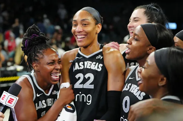 Sep 30, 2025; Las Vegas, Nevada, USA; Las Vegas Aces guard Chelsea Gray (12), Las Vegas Aces center A'ja Wilson (22), and Las Vegas Aces guard Jackie Young (0) react during an interview after defeating the Indiana Fever 107-98 in overtime of game five of the second round for the 2025 WNBA Playoffs at Michelob Ultra Arena. Mandatory Credit: Stephen R. Sylvanie-Imagn Images