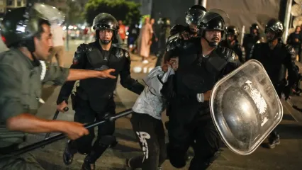 A boy is detained as youth led protests turned violent, in Sale, Morocco, Oct. 1, 2025 (AP photo by Mosa'ab Elshamy).