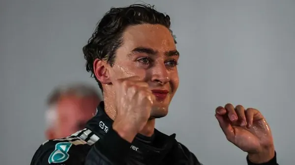A champagne-covered George Russell lifts his arms in celebration after winning the Singapore Grand Prix 