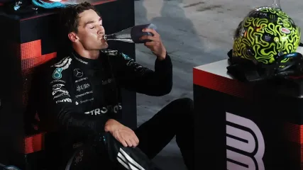George Russell sits down and drinks from a water bottle after winning the Singapore Grand Prix
