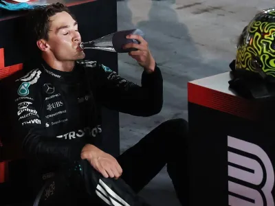 George Russell sits down and drinks from a water bottle after winning the Singapore Grand Prix