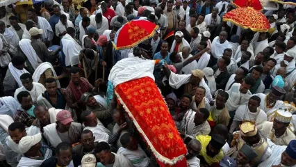 Mourners, some with umbreallas, carry a coffin