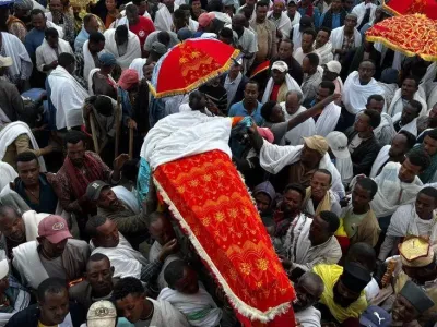 Mourners, some with umbreallas, carry a coffin