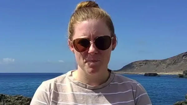 Nikita Goddard on the coast of Gran Canaria with blue sea and coastline behind her