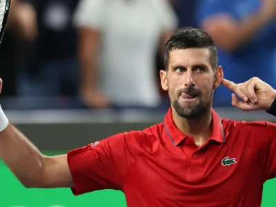 Novak Djokovic points to his ear as the crowd applauds him taking the second set to level the match