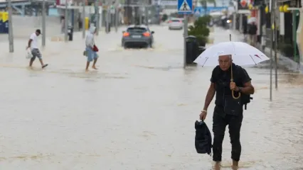 People walk along a flooded street in Ibiza on September 30, 2025 (Vicent MARI)
