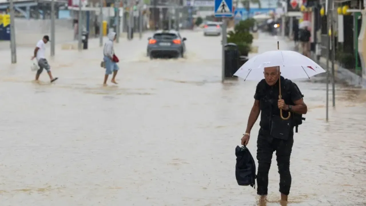 People walk along a flooded street in Ibiza on September 30, 2025 (Vicent MARI)