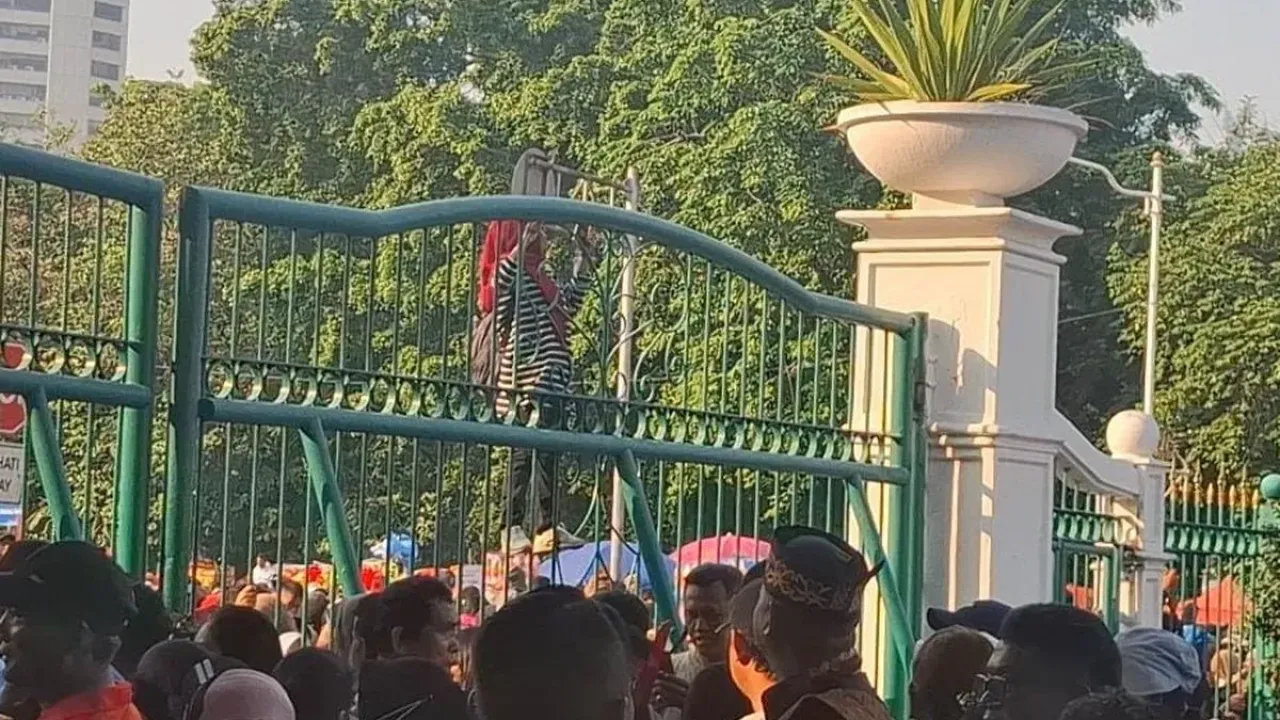 Seorang ibu nekat memanjat pagar pintu timur masuk Monumen Nasional (Monas), Jakarta, Minggu (5/10/2025) untuk menyaksikan perayaan HUT ke-80 TNI.