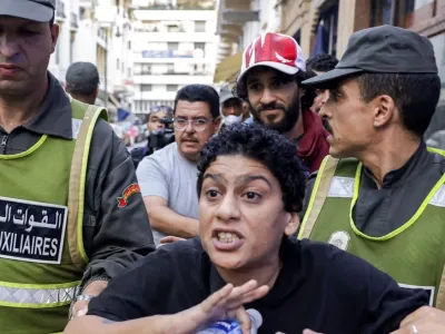 Two security force personnel detain a protester